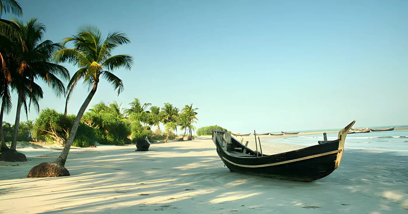 Palm trees and a wooden fishing boat on a white-sand beach by the Bay of Bengal